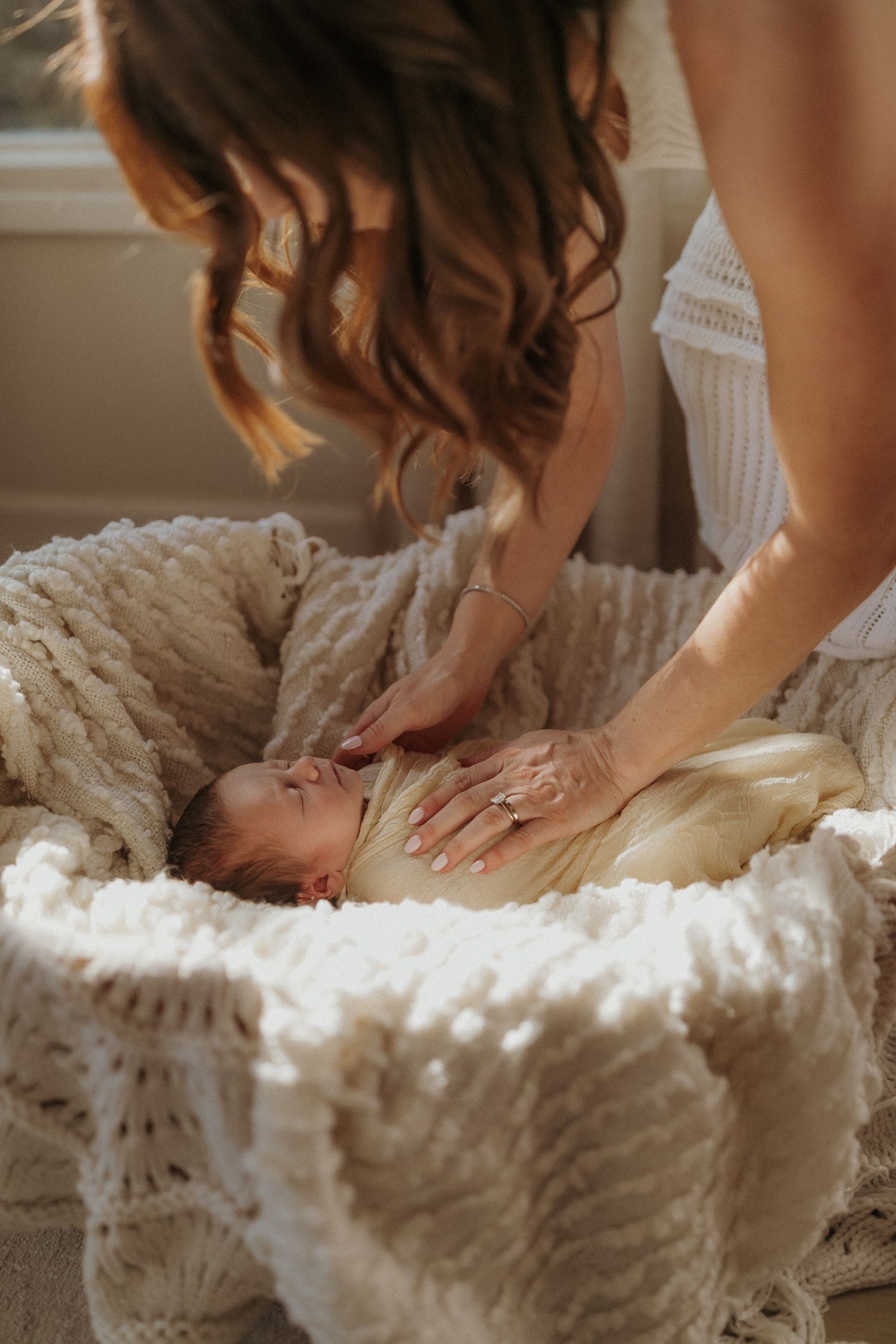 Close-up shots of hands caressing white lace fabric in sequence. San Diego Newborn Photographer.