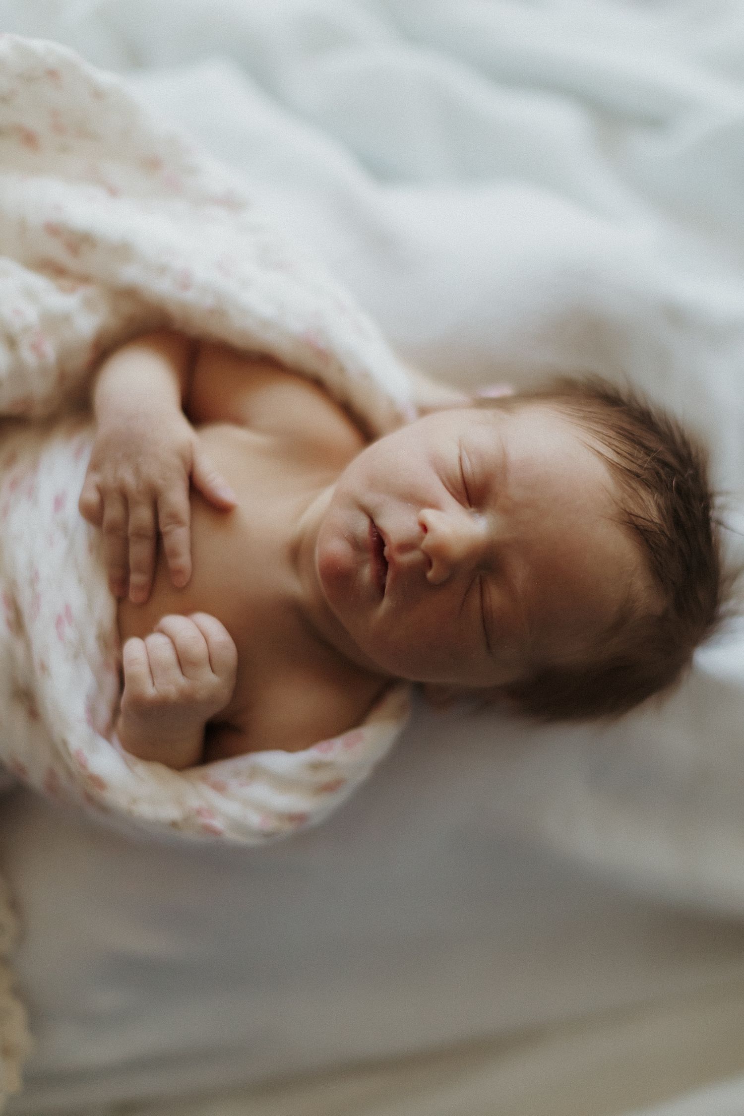 Peaceful sleeping newborn wrapped in soft white blankets. San Diego Newborn Photographer.