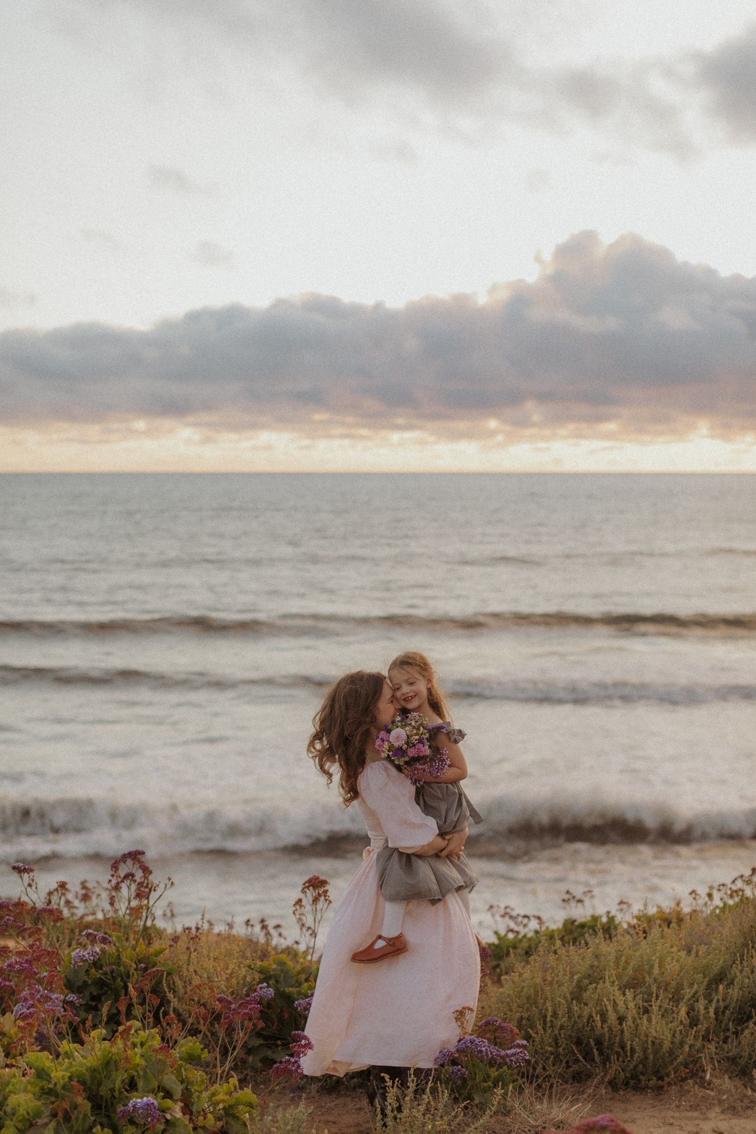 Children in white dresses playing by the ocean at sunset. San Diego Family Photographer.
