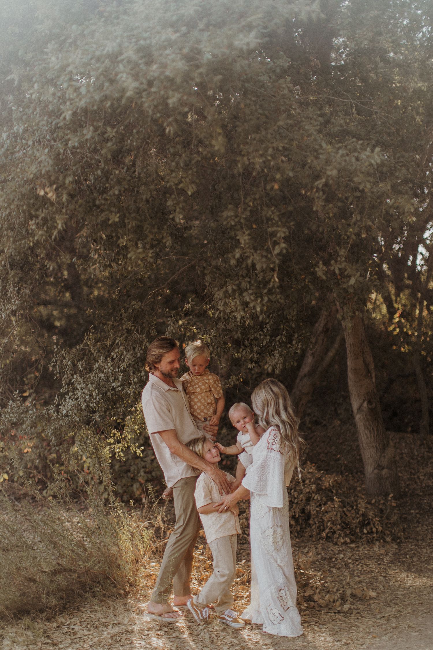 A family shares joyful moments together in a San Diego natural outdoor setting with golden sunlight filtering through trees.