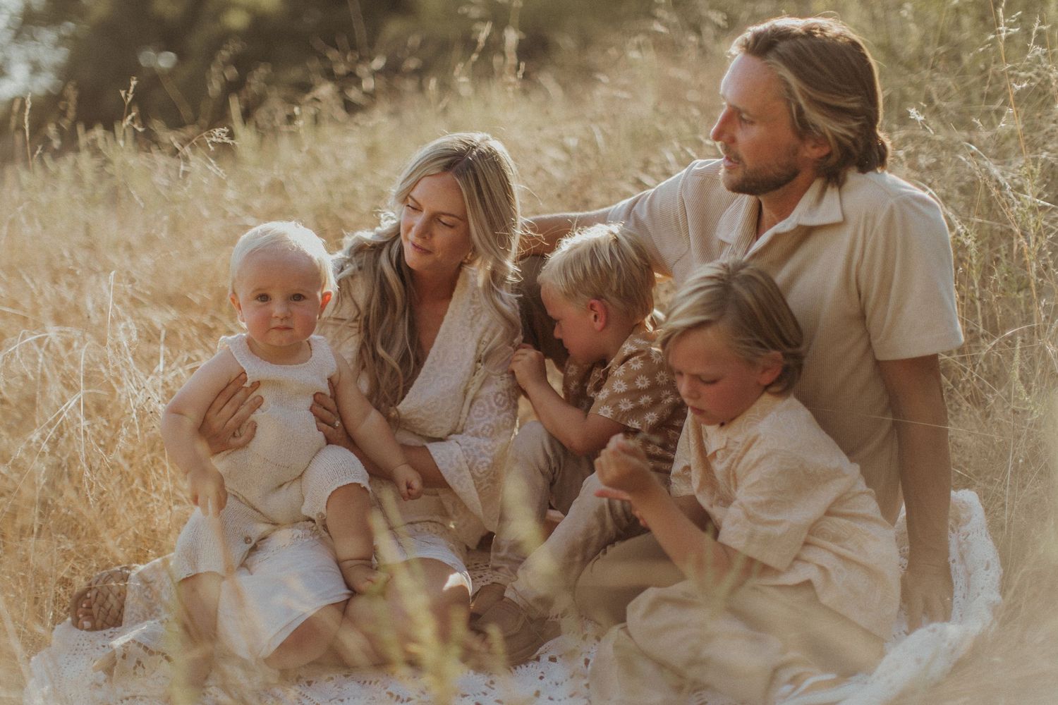 Family sharing tender moments together in a golden sunlit field.