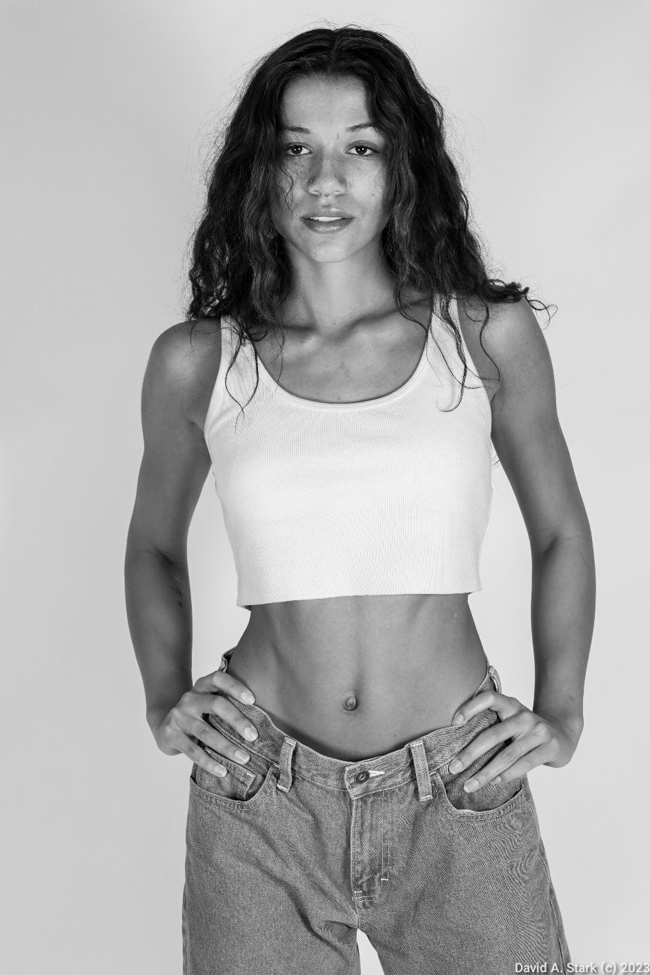 Black and white portrait of athletic model in crop top and jeans.