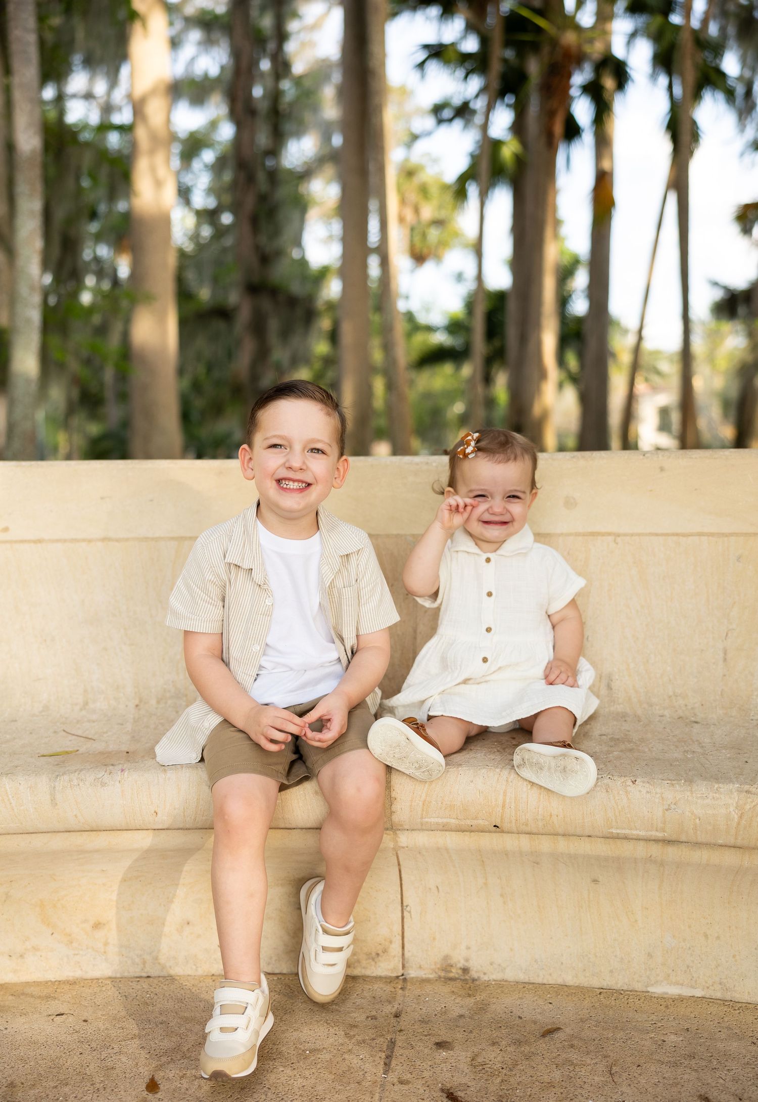 Children sitting together on a curved stone bench in a scenic outdoor setting.