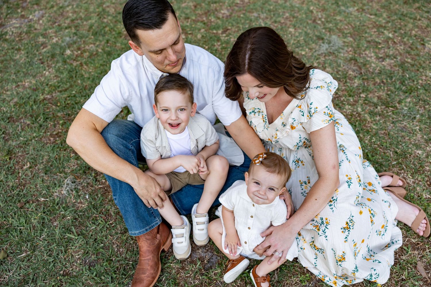 A relaxed family photoshoot on grass with natural lighting and soft expressions.