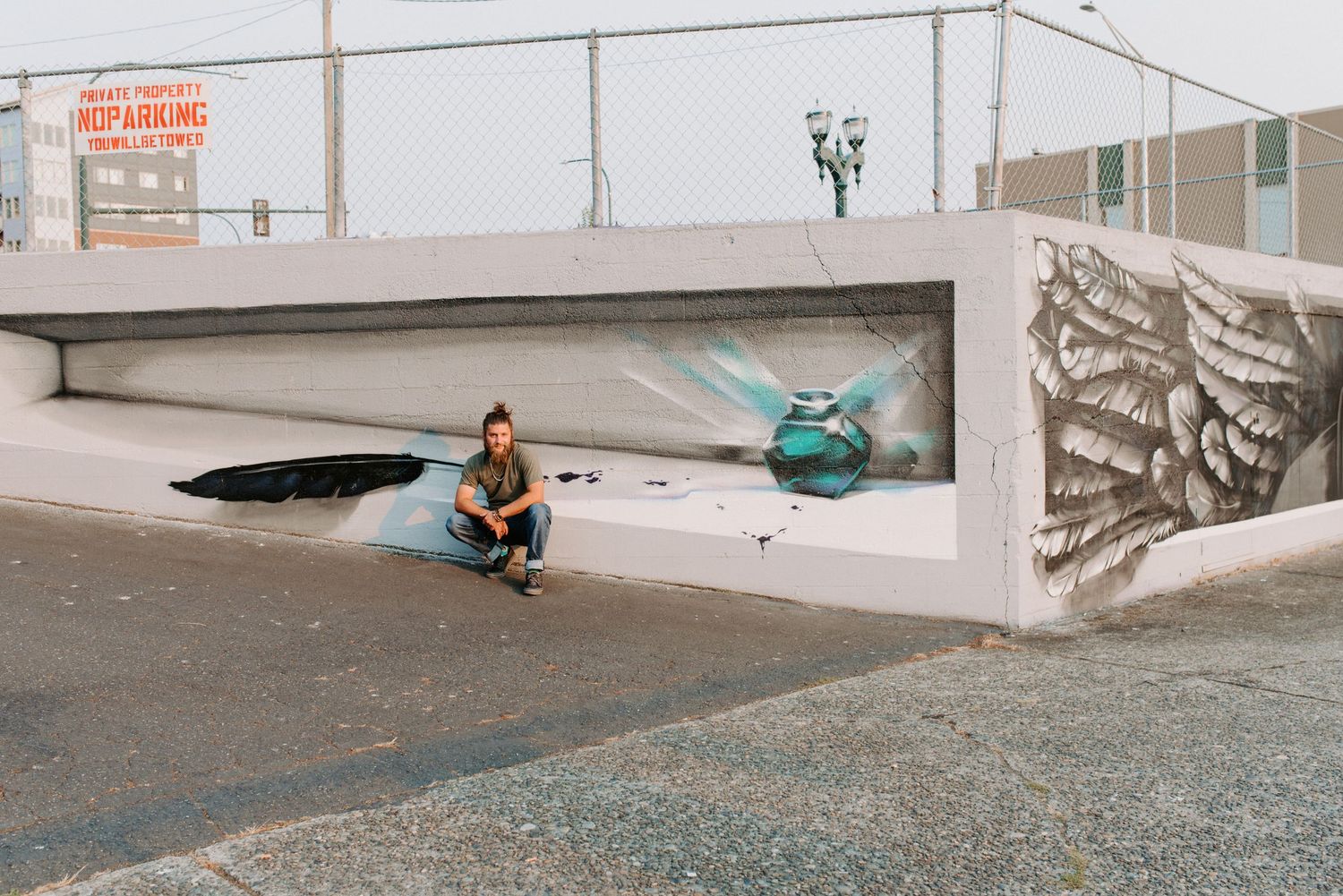 Person sitting in urban concrete structure with street art and skateboard.