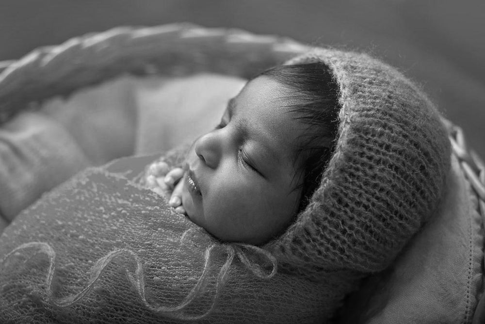 back lit black and white close up of newborn baby with knitted hat and blanket in studio newborn photography*
