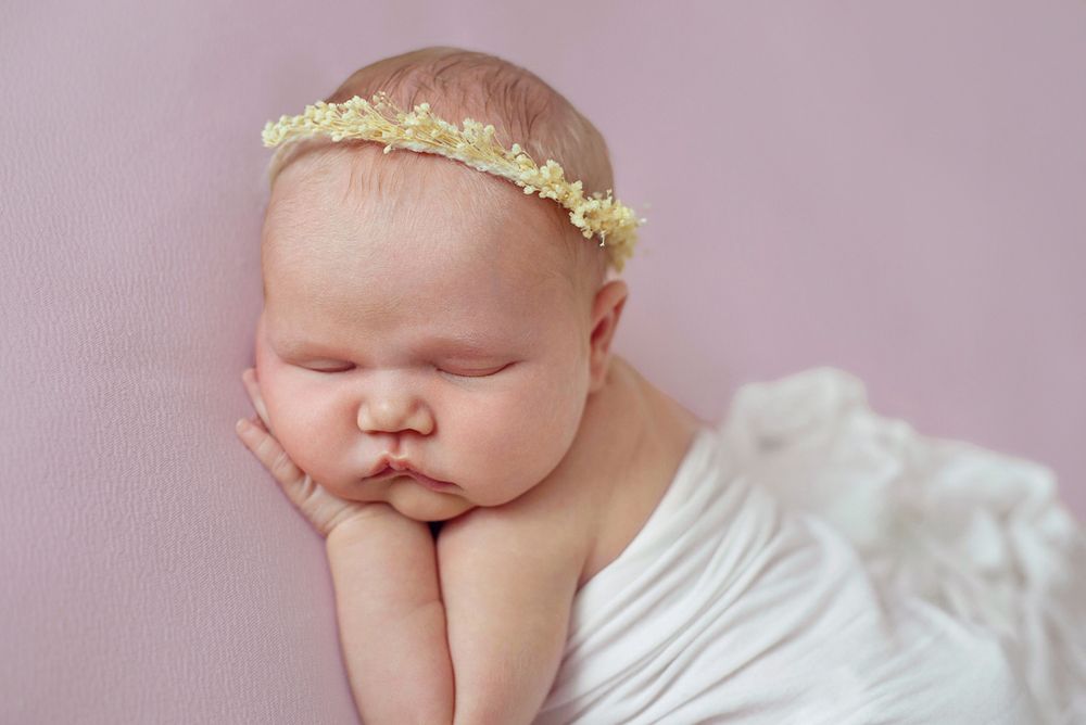 in studio posed newborn baby photography Baltimore Ontario, close up of face on purple backdrop with white blanket*