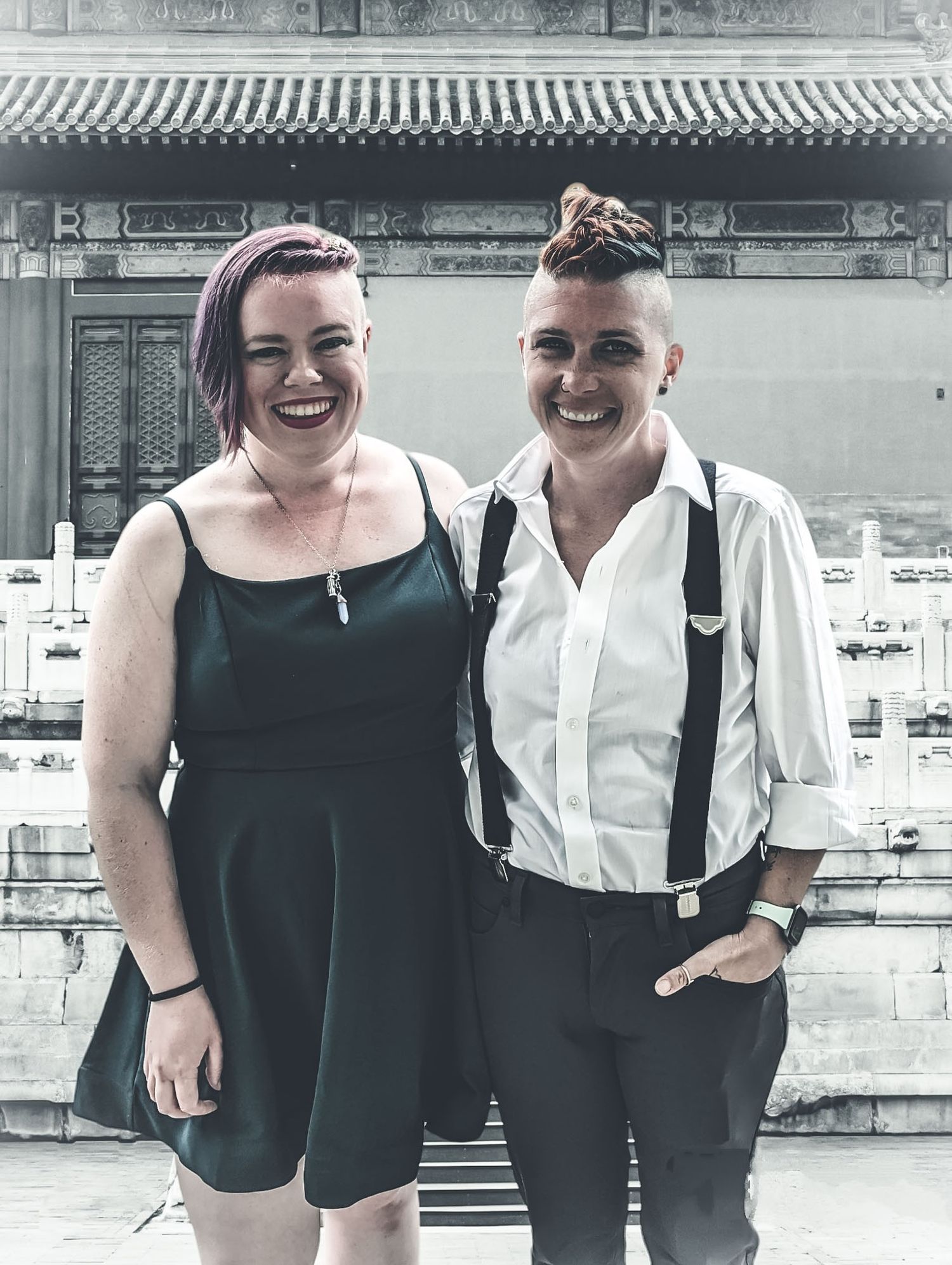 Two stylish friends pose together in front of an ornate Asian temple building.