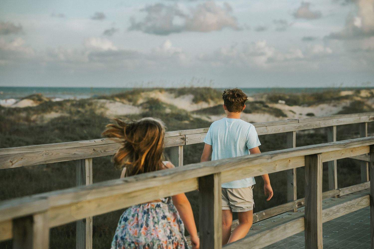 Two children walk down a pier in Matagorda TX during golden hour at a family photography session.