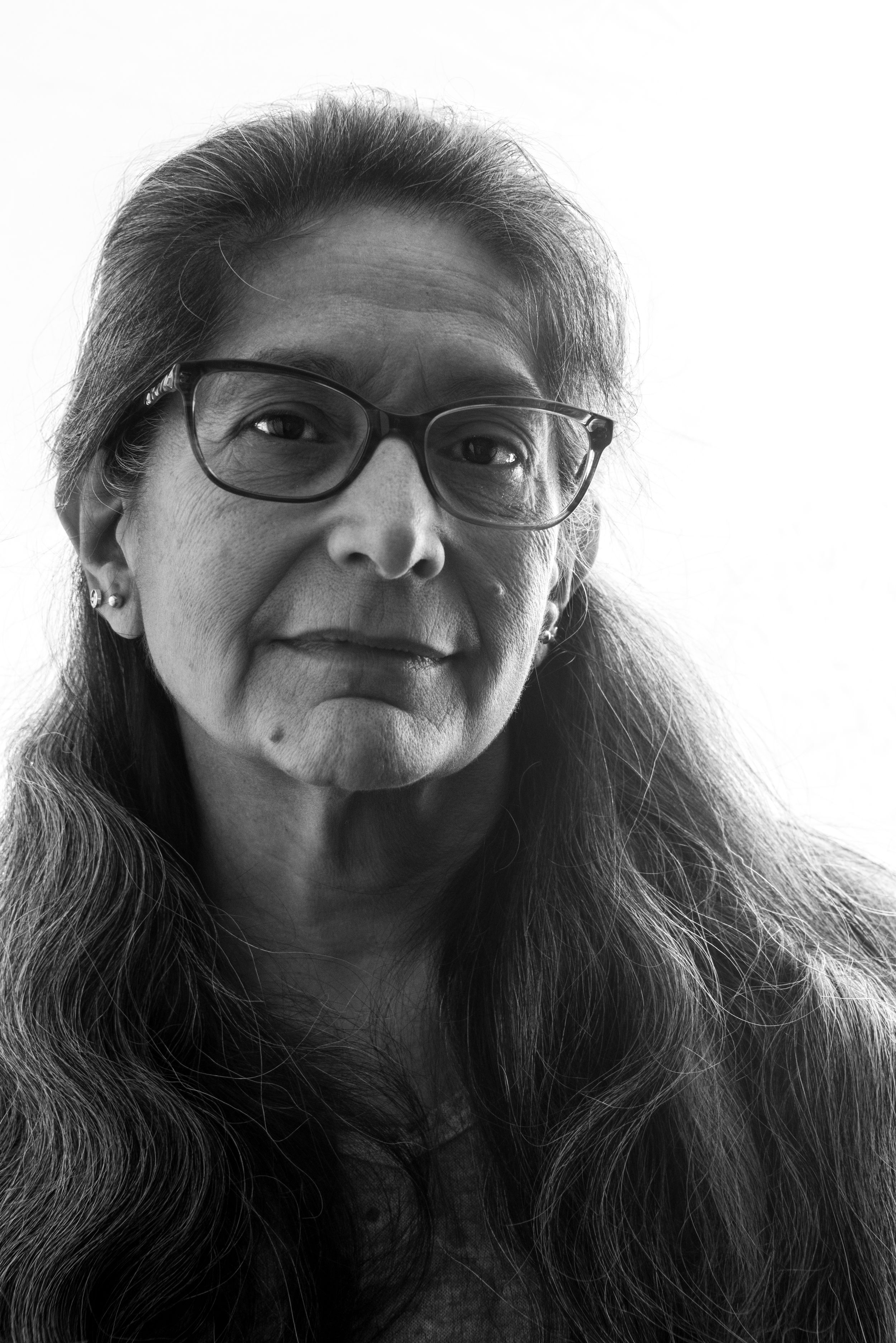 Woman with a white background, posing for a dramatic headshot.