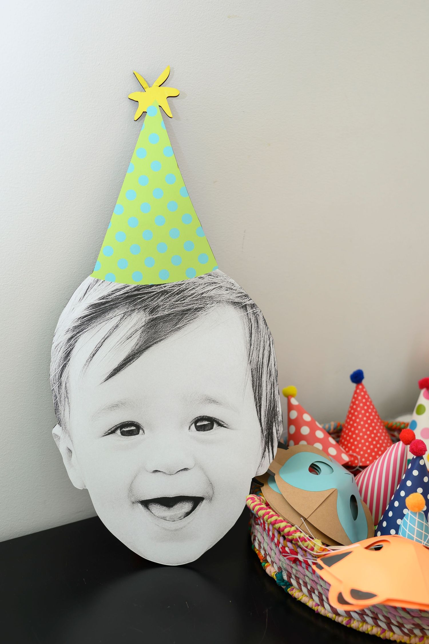 Black and white photo print wearing a colorful paper party hat displayed next to festive party decorations.