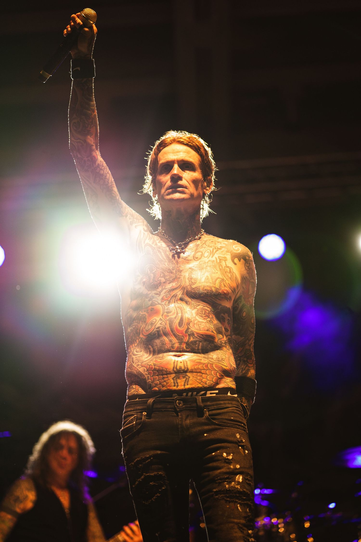 Performer raises fist triumphantly on stage with dramatic backlighting.