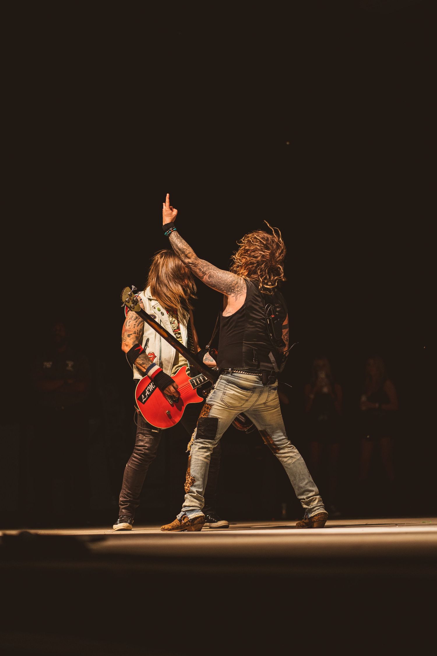 Two performers on stage with guitarist flipping hair during energetic rock performance.