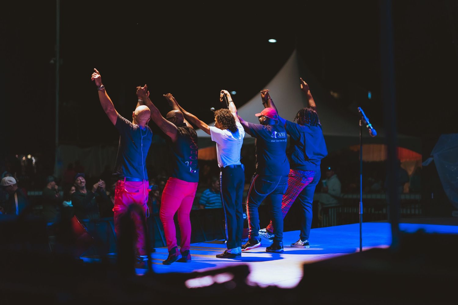Group of performers dancing in synchronization on stage under blue lighting.
