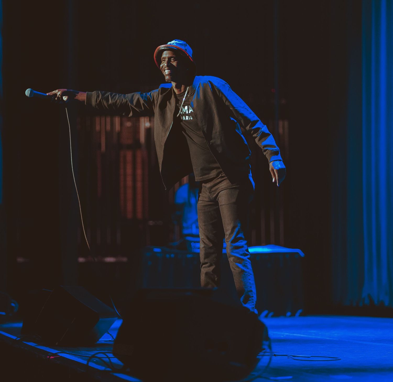A performer on stage illuminated by blue lighting during a live show.
