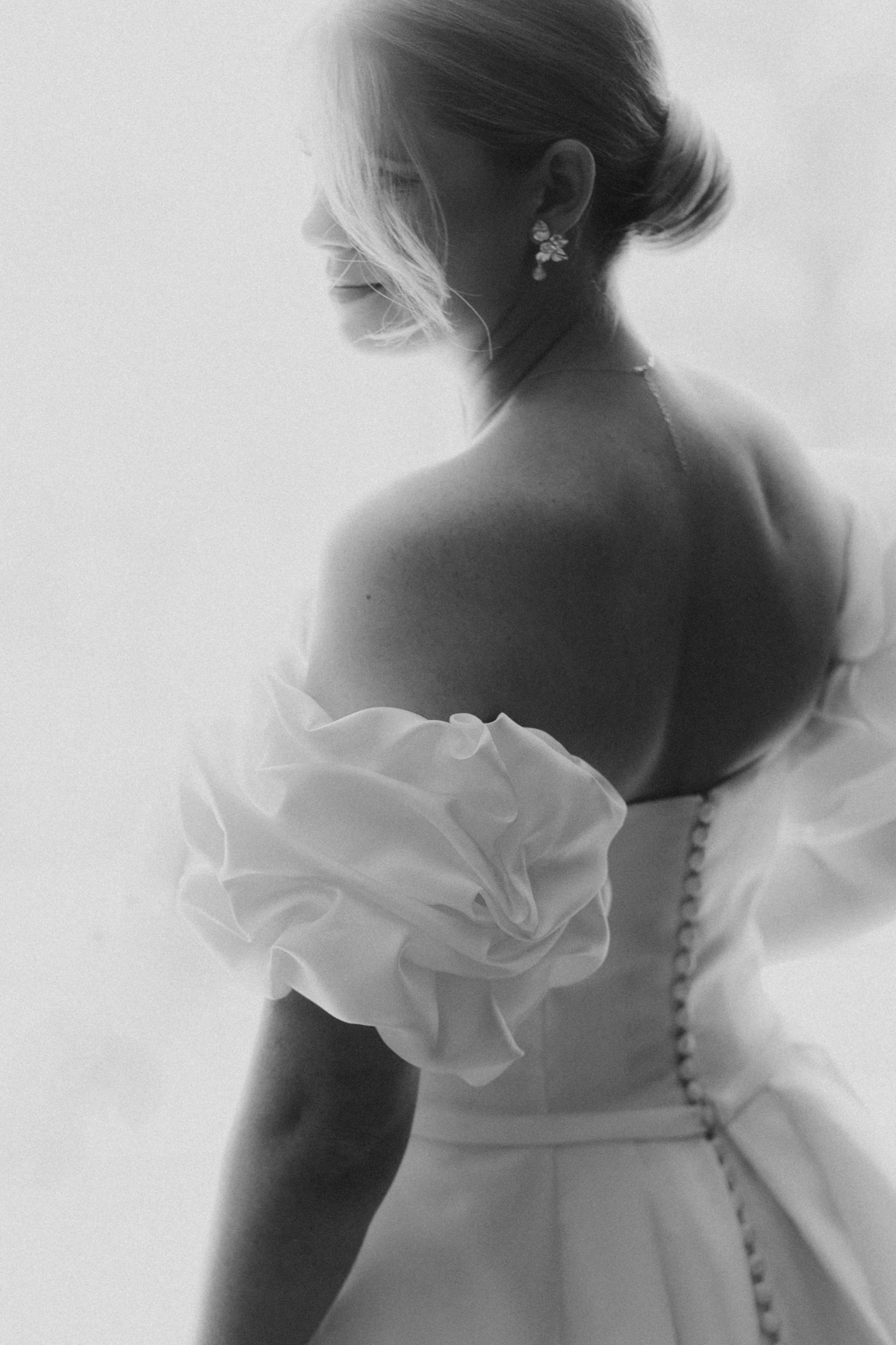 A dreamy black and white photo series shows the back of a wedding dress with delicate buttons and ruffled details.