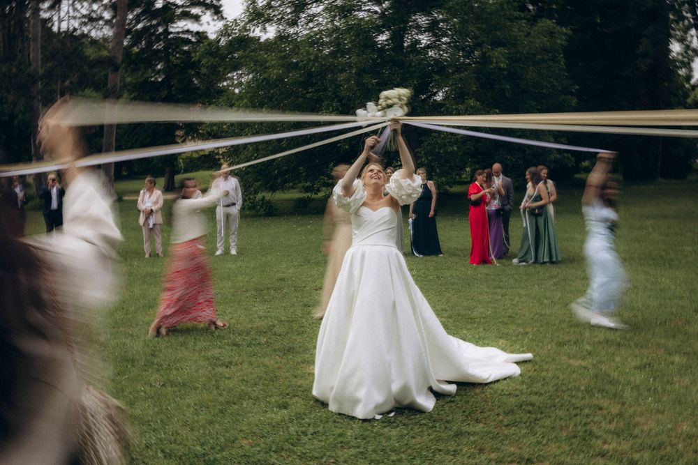 A wedding celebration takes place on a grassy lawn with people dancing and enjoying the outdoor festivities.