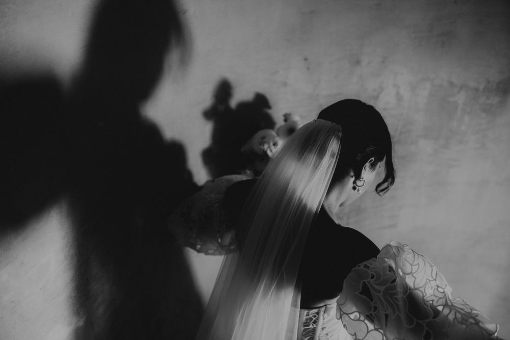 A black and white artistic photograph shows silhouettes of people dancing in a dark, atmospheric setting.