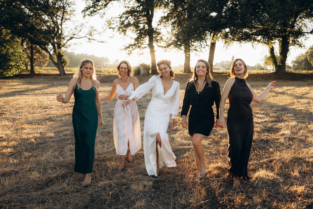 A group in black and white outfits poses together at sunset in a grassy field with trees in the background.