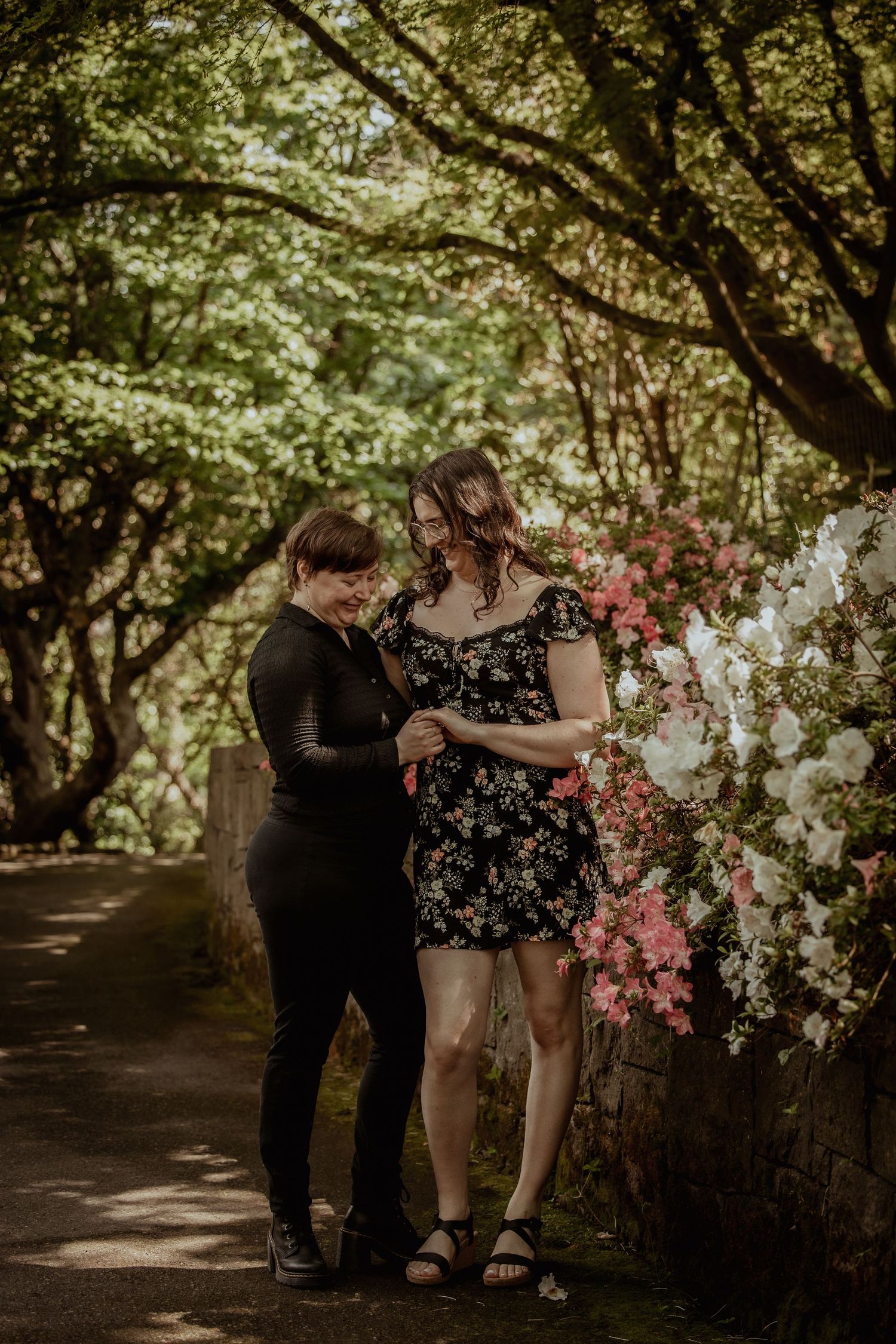 A couple shares an intimate moment under blooming cherry trees in a romantic outdoor garden setting.