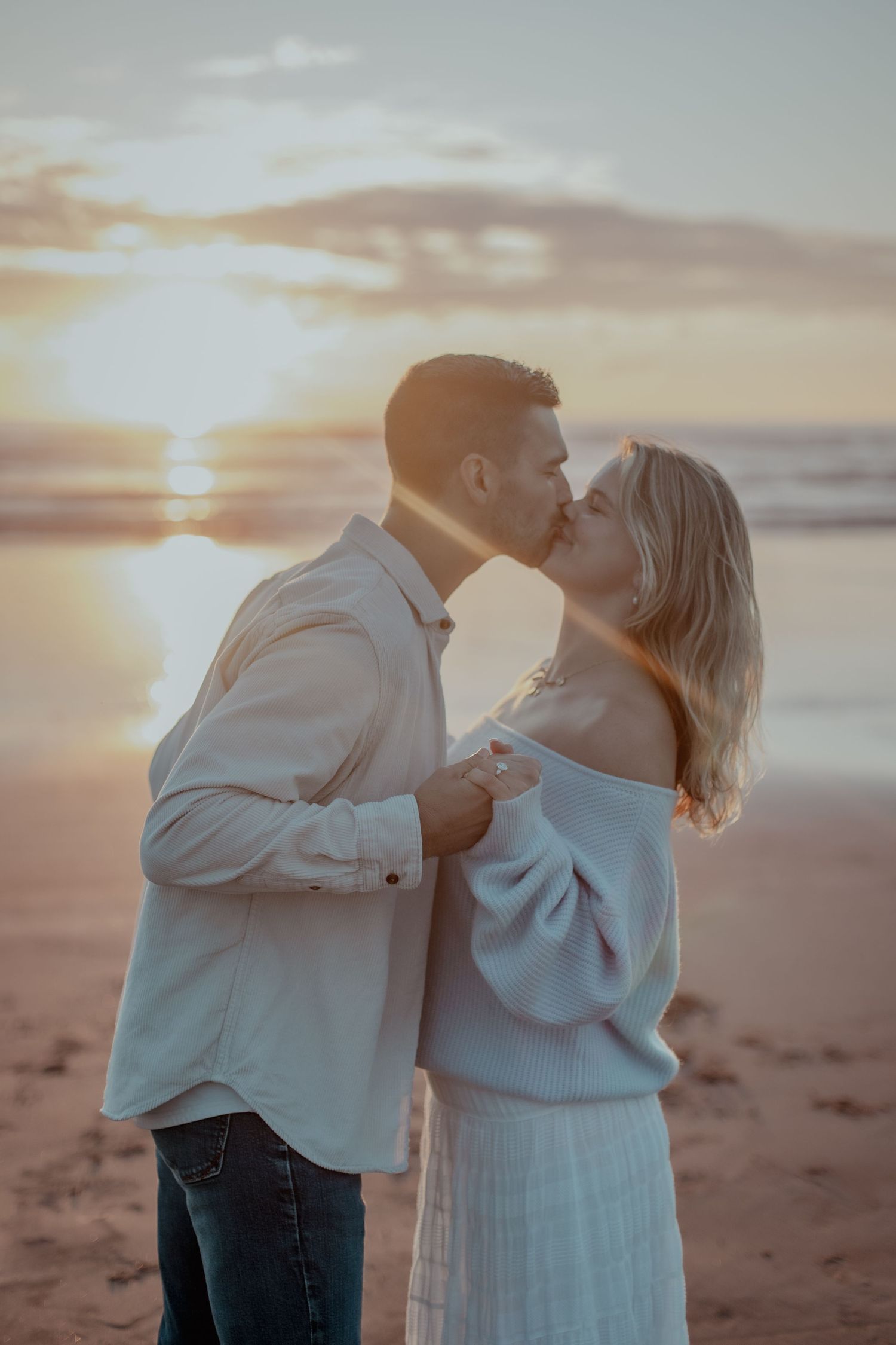 Romantic couple sharing an intimate moment on the beach during golden hour.