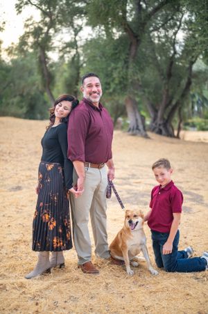 Family portrait with dog in outdoor setting featuring earthy tones and natural lighting.