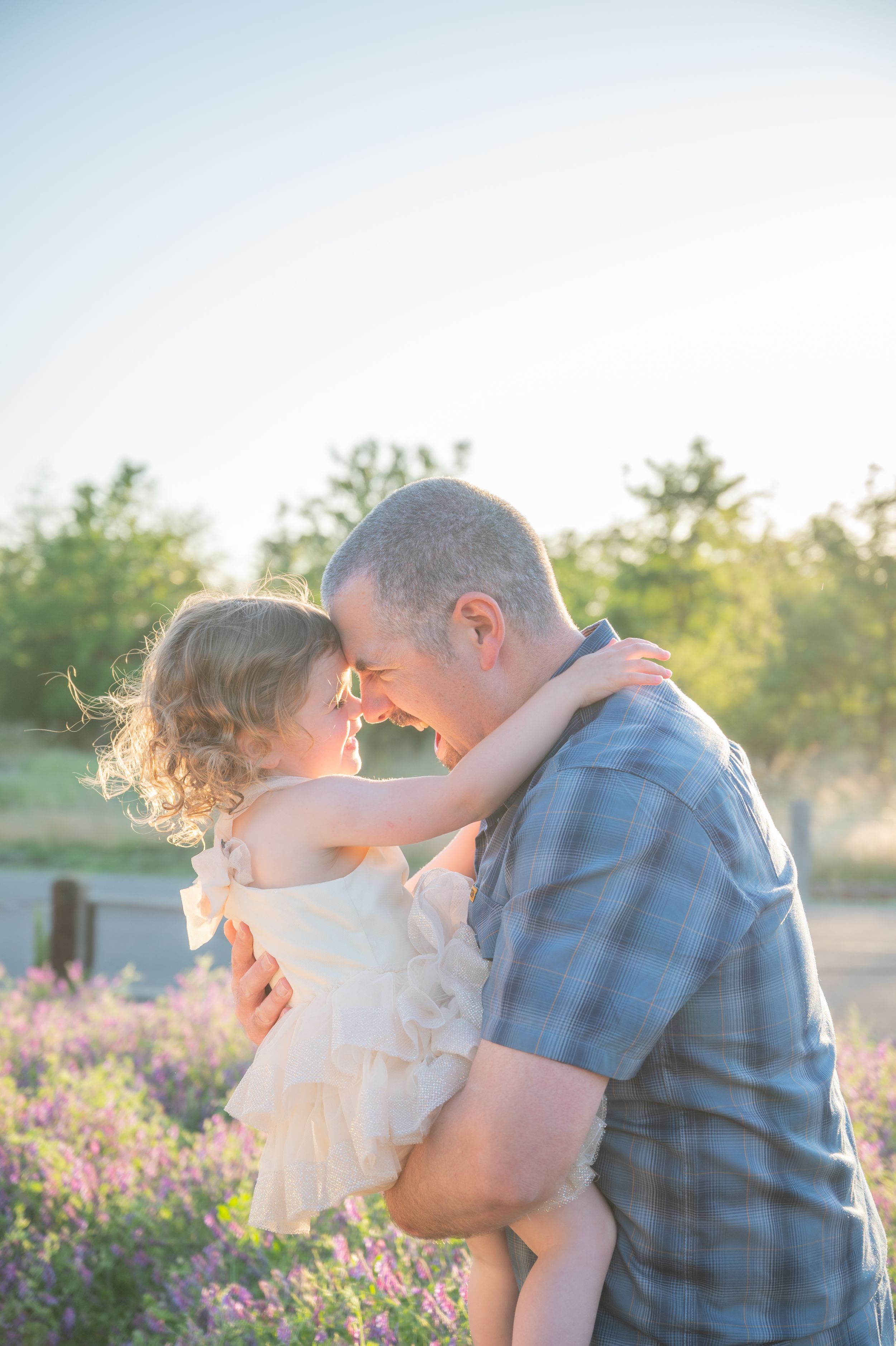 A tender moment captured between parent and child against a blossoming garden at sunset.