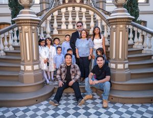 A group poses on ornate marble steps with checkerboard tiles and decorative stone pillars at an elegant location.