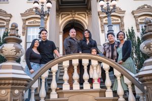 A group of people standing together on an ornate stone staircase with decorative balusters and classical architecture.