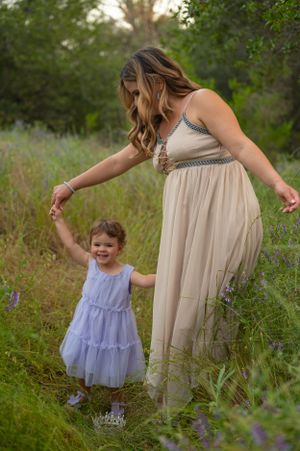 A joyful moment of dancing together in flowing dresses among wild grass and flowers.