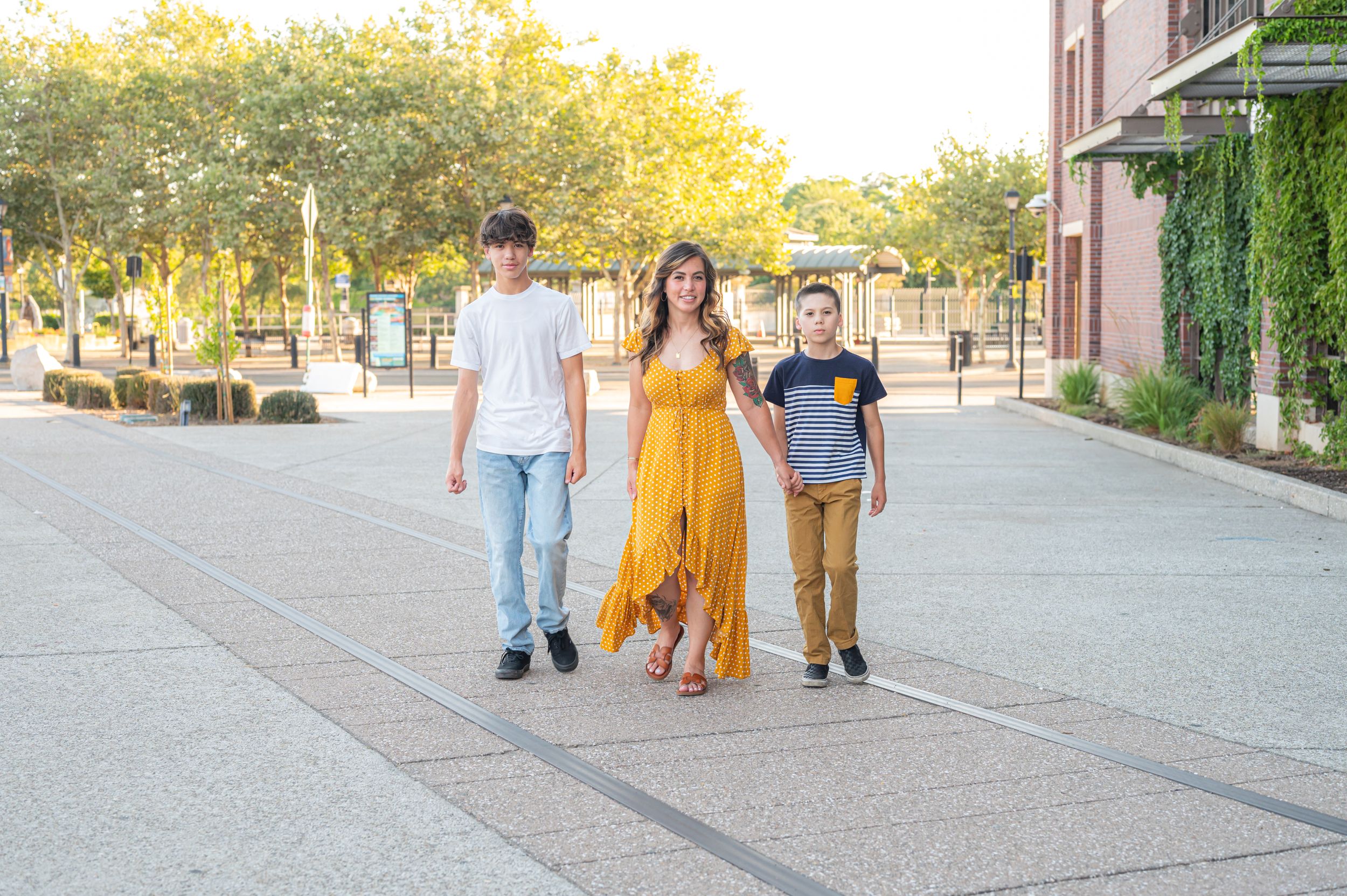 Three people walking together on urban pathway at sunset.