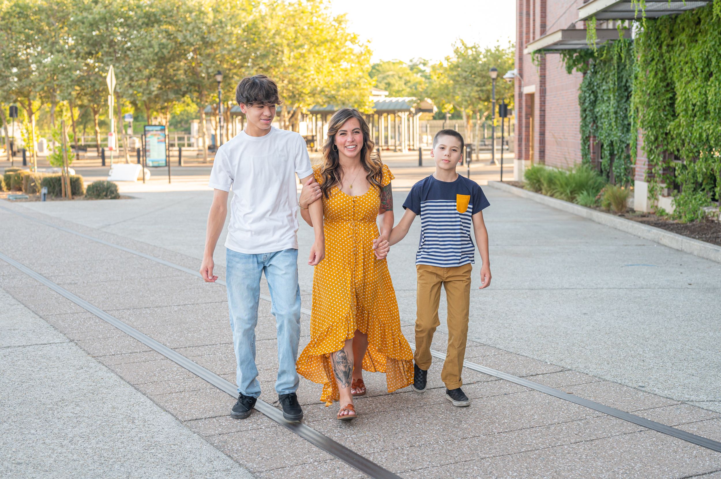 Three people walking together on sidewalk during golden hour.