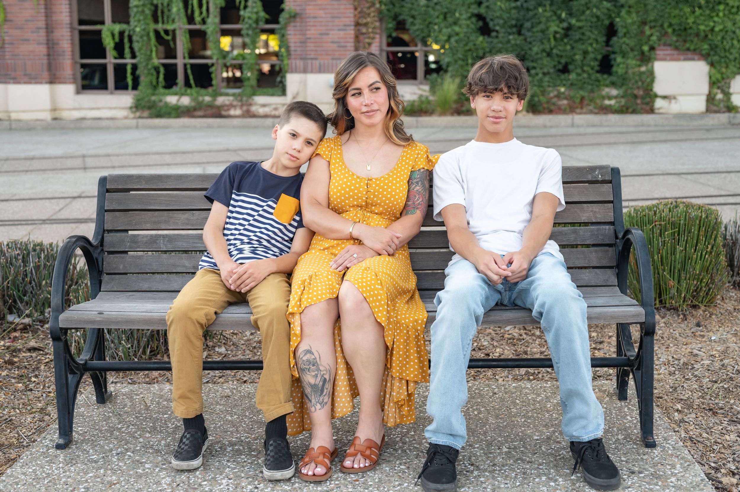 Three people sitting on park bench in casual attire during daytime.
