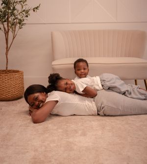 A relaxed family moment showing playful bonding on a carpeted floor with a cream-colored couch in background.