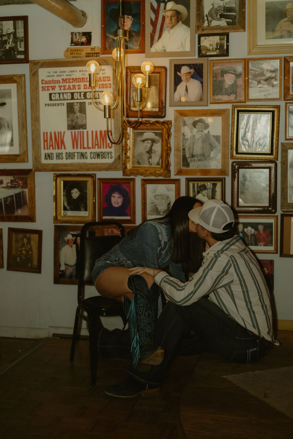 A wall covered in vintage photographs and memorabilia in what appears to be a country music museum or historic venue.