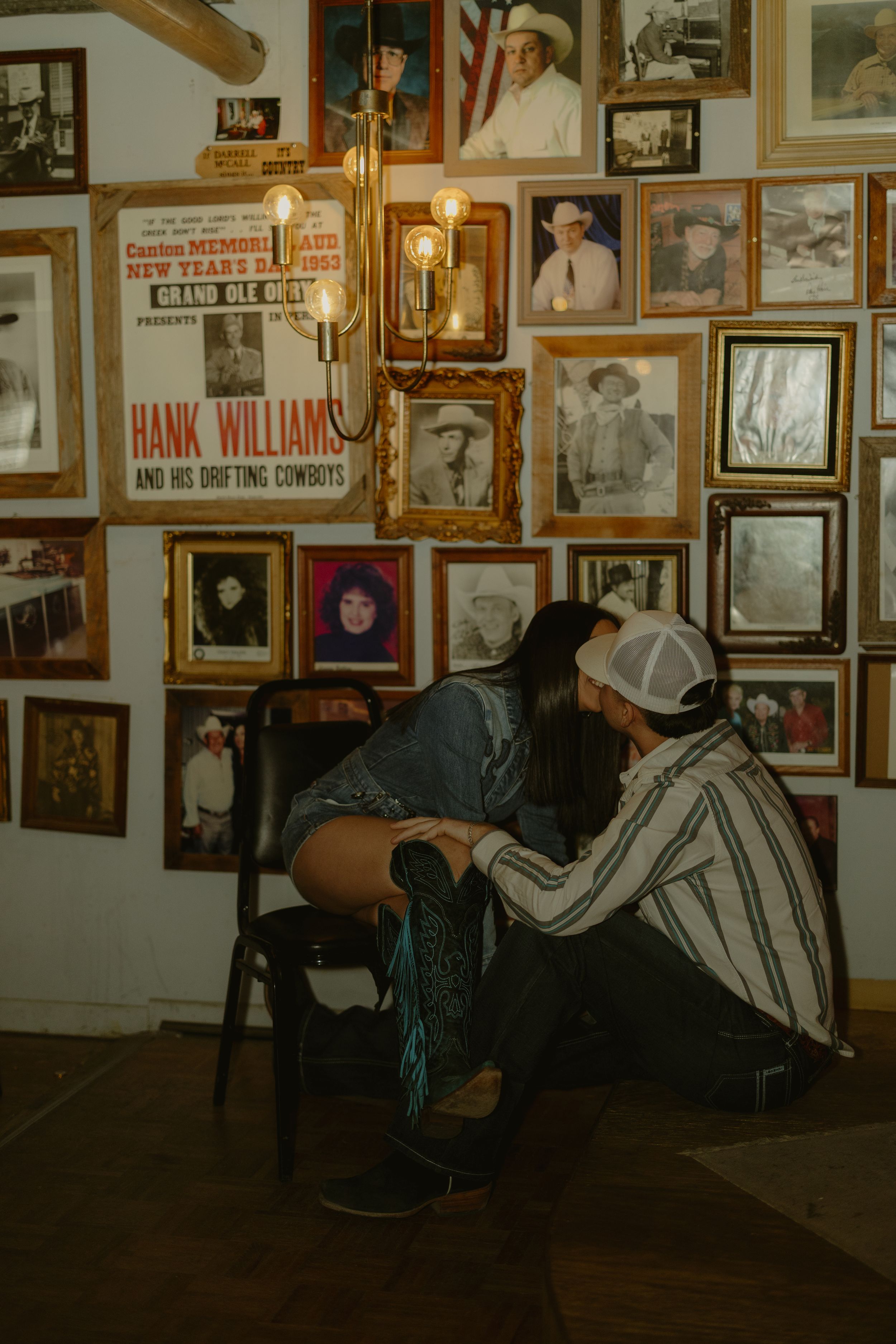 A wall covered in vintage photographs and memorabilia in what appears to be a country music museum or historic venue.
