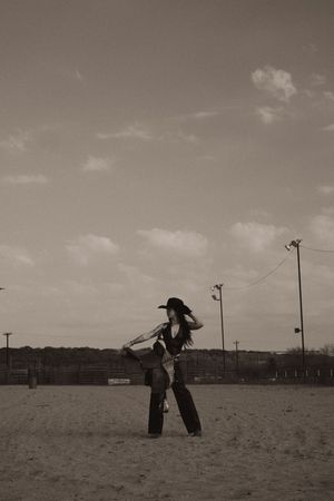 Black and white photo of silhouettes playing in an open field under a cloudy sky.