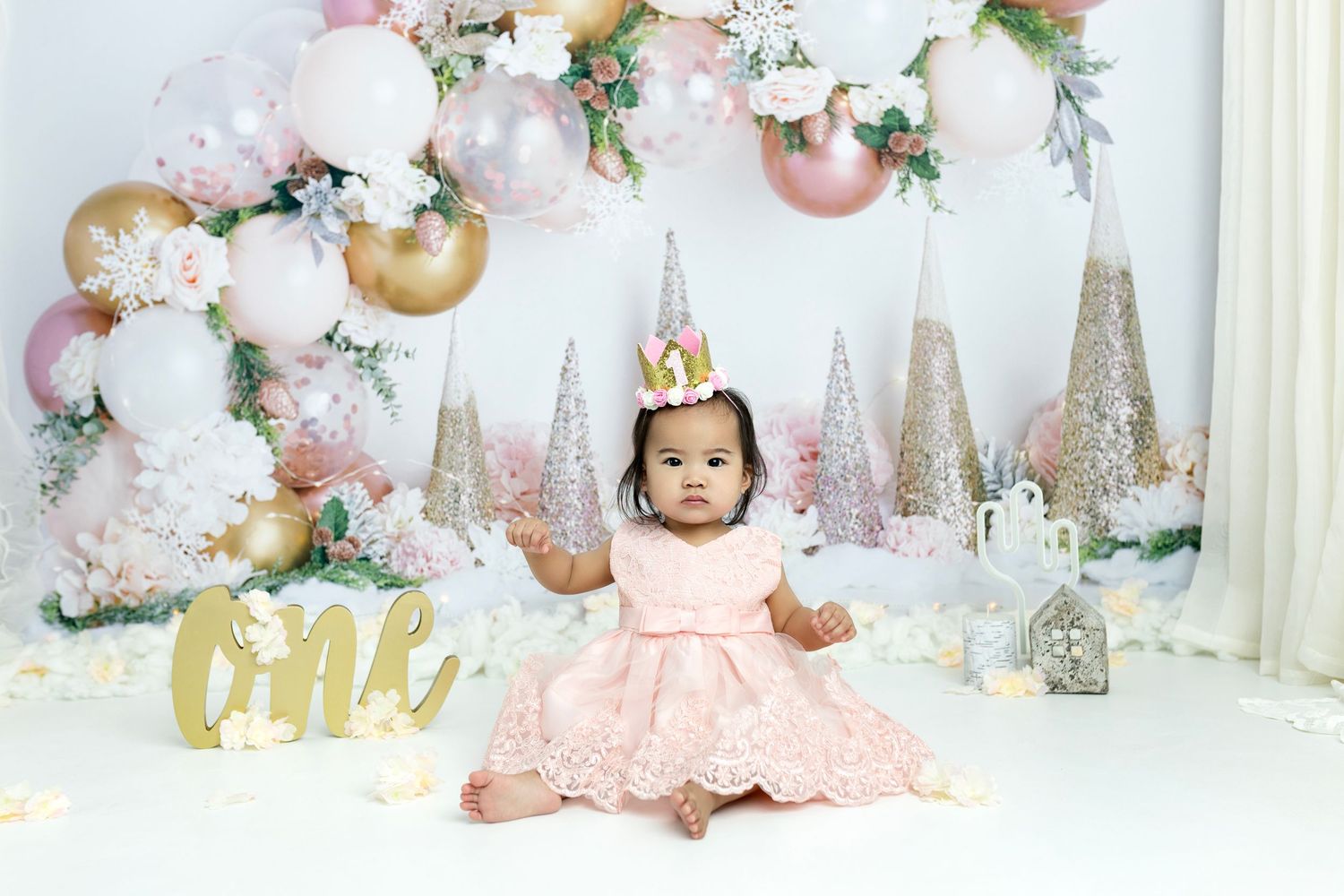 Dreamy pink and white first birthday setup with balloons and sparkly accents.