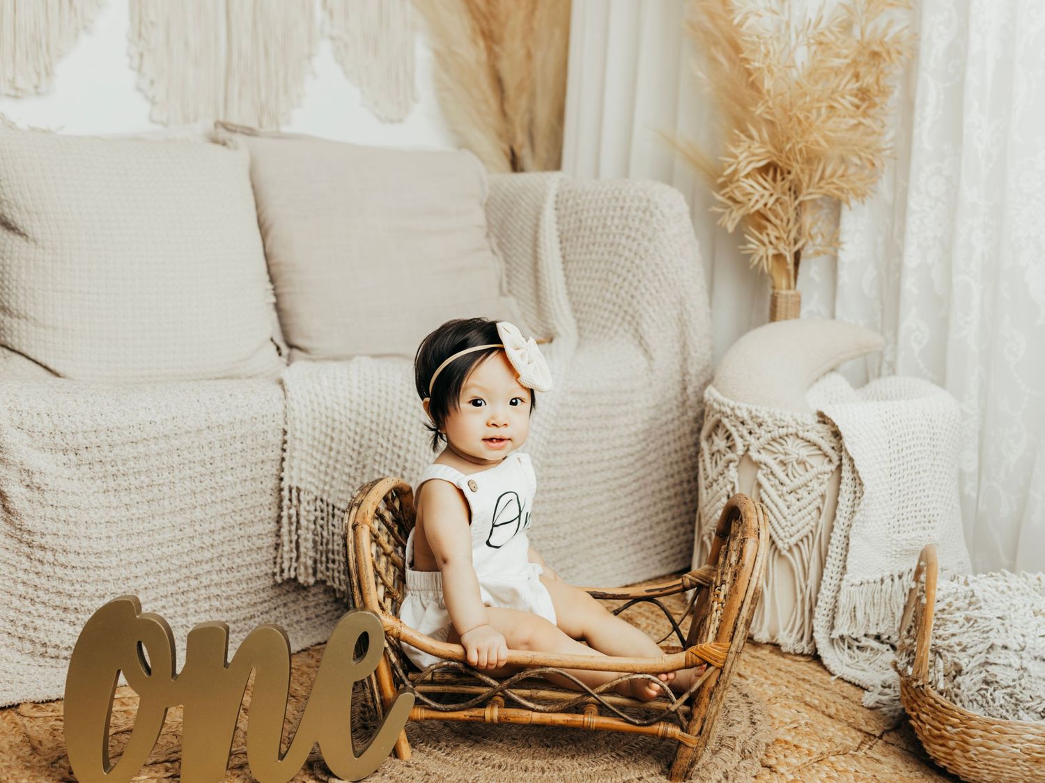 Boho-inspired cake smash photo setup with neutral colors and dried pampas grass.