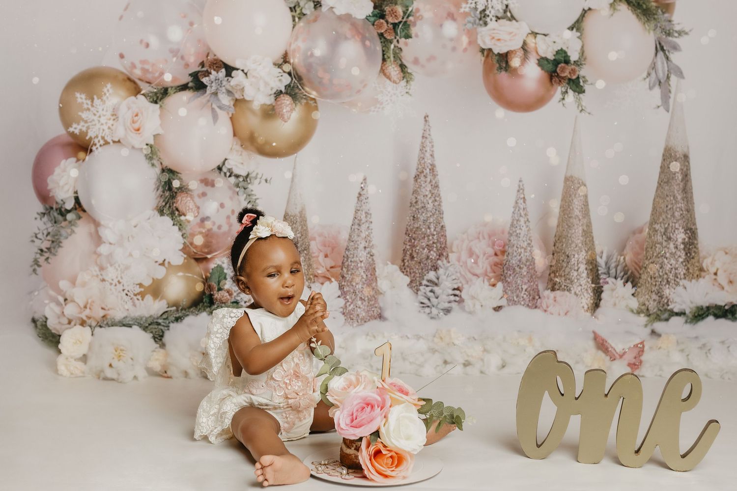 Winter wonderland cake smash setup with balloon arch and pink decorations.