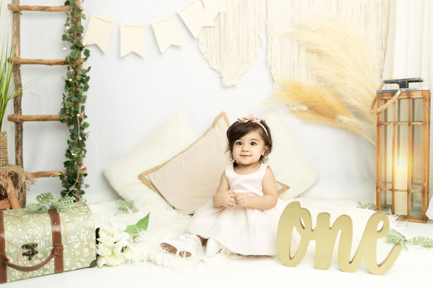 Neutral toned birthday photo backdrop with gold 'one' lettering and rustic elements.