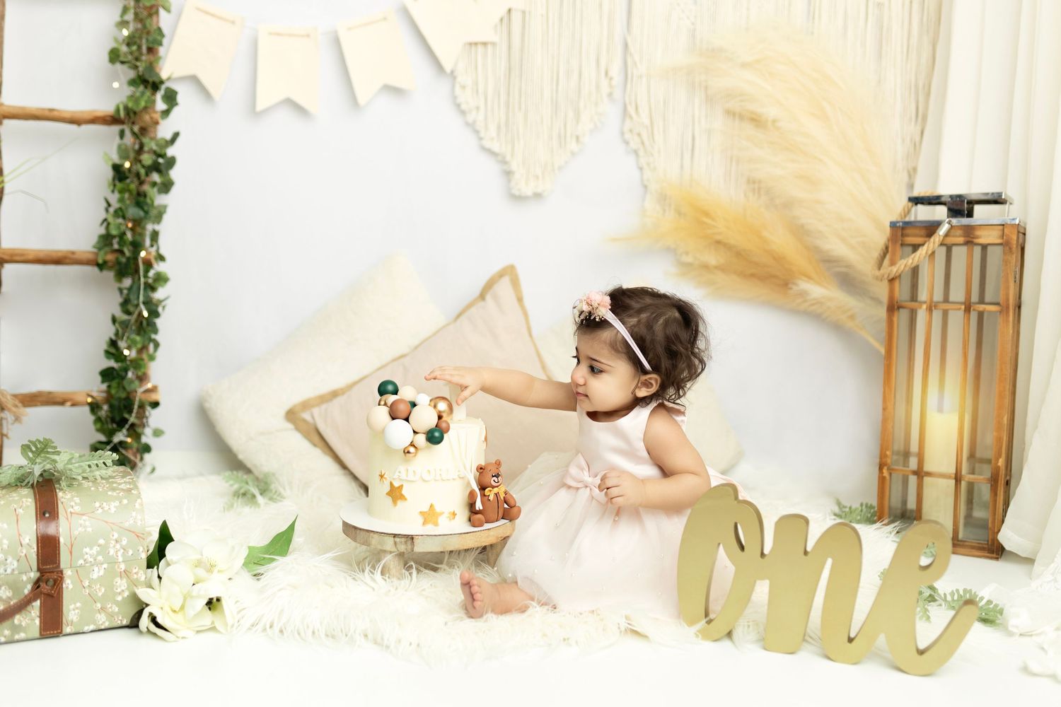 First birthday photo setup featuring wooden accents and white fabric backdrop.