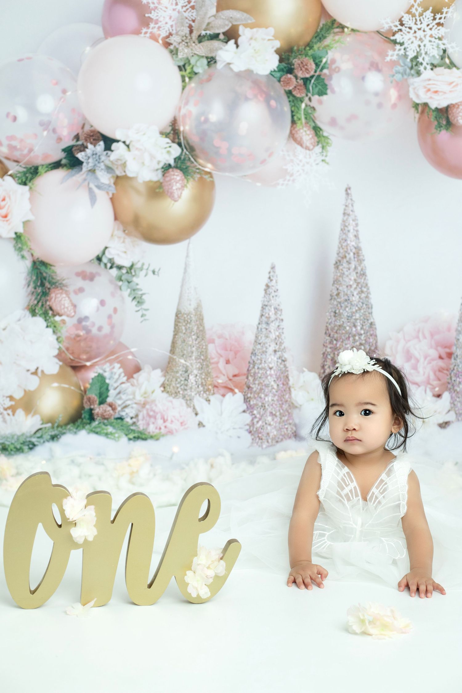 Elegant pink and gold birthday backdrop with balloons, flowers and glitter trees.