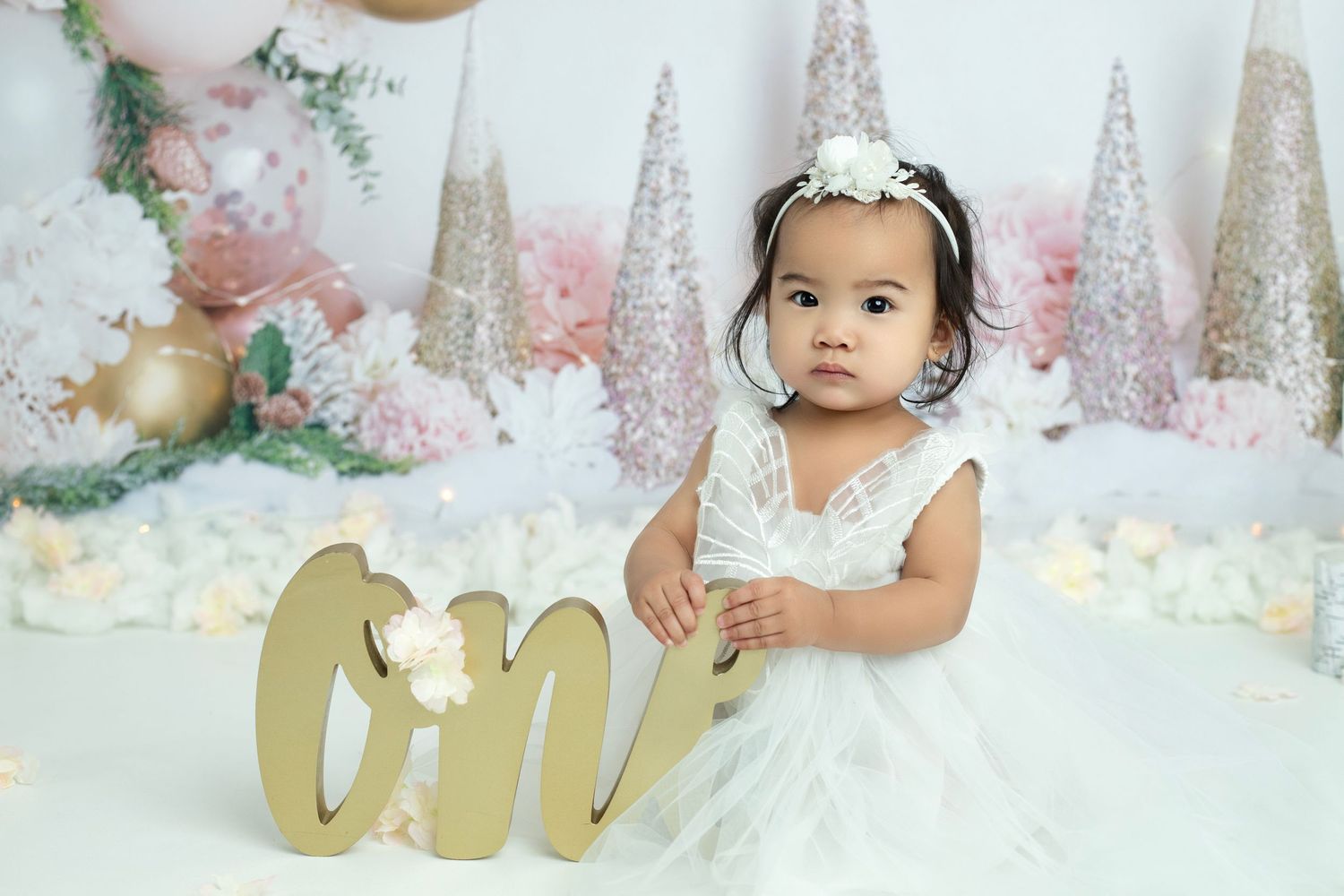 Pink floral backdrop with gold decor and white accents creates an elegant photography setting.