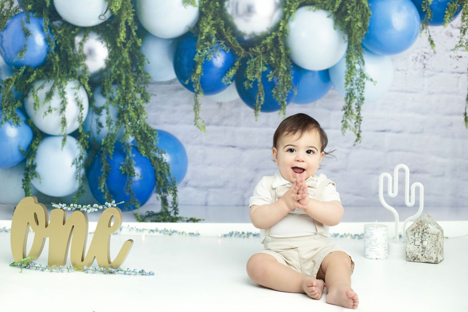 Blue and white balloon arch with greenery creates a festive first birthday backdrop.
