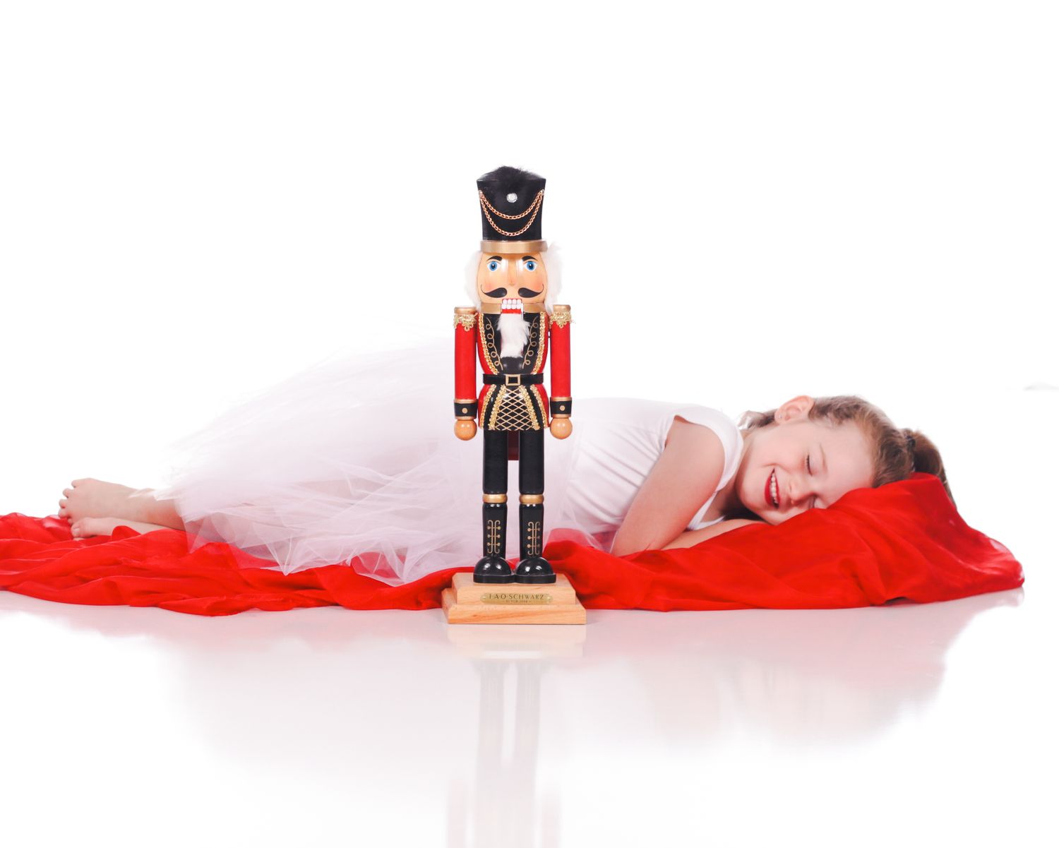 Creative holiday photo series with nutcracker decoration and flowing red fabric.