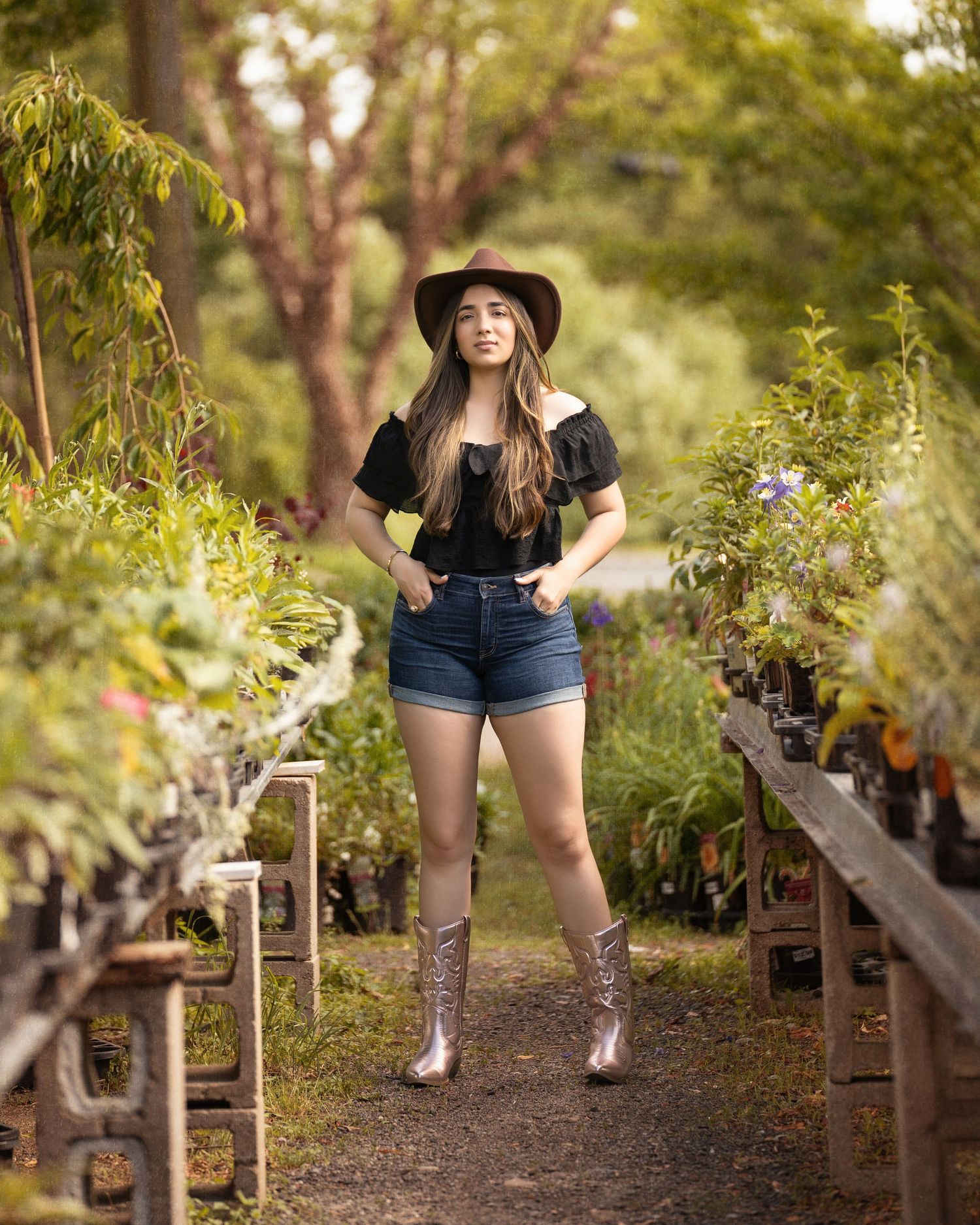 Casual portrait in black hat and denim shorts at plant nursery.