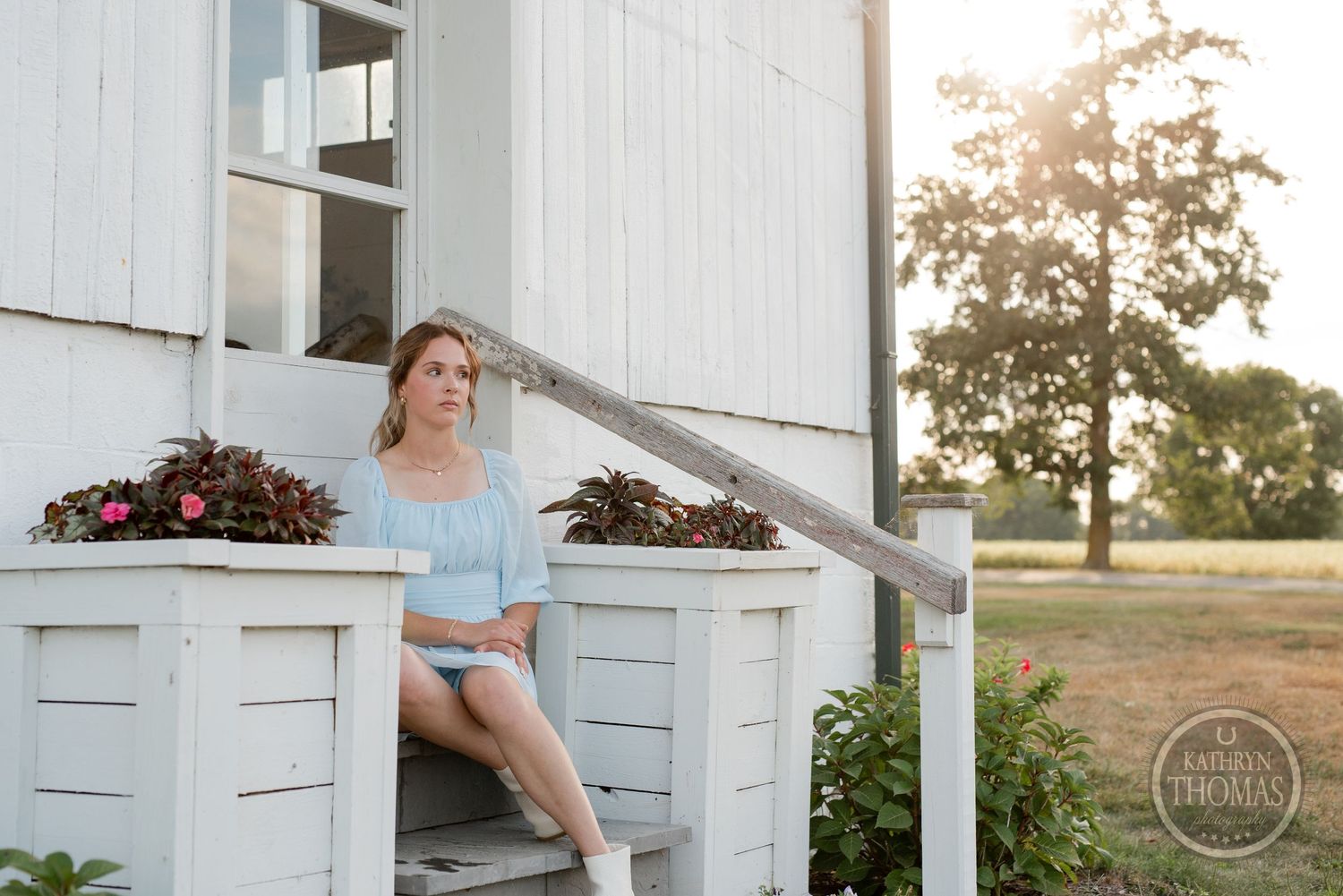 A light blue dress and white shoes create a romantic farmhouse porch scene at sunset.