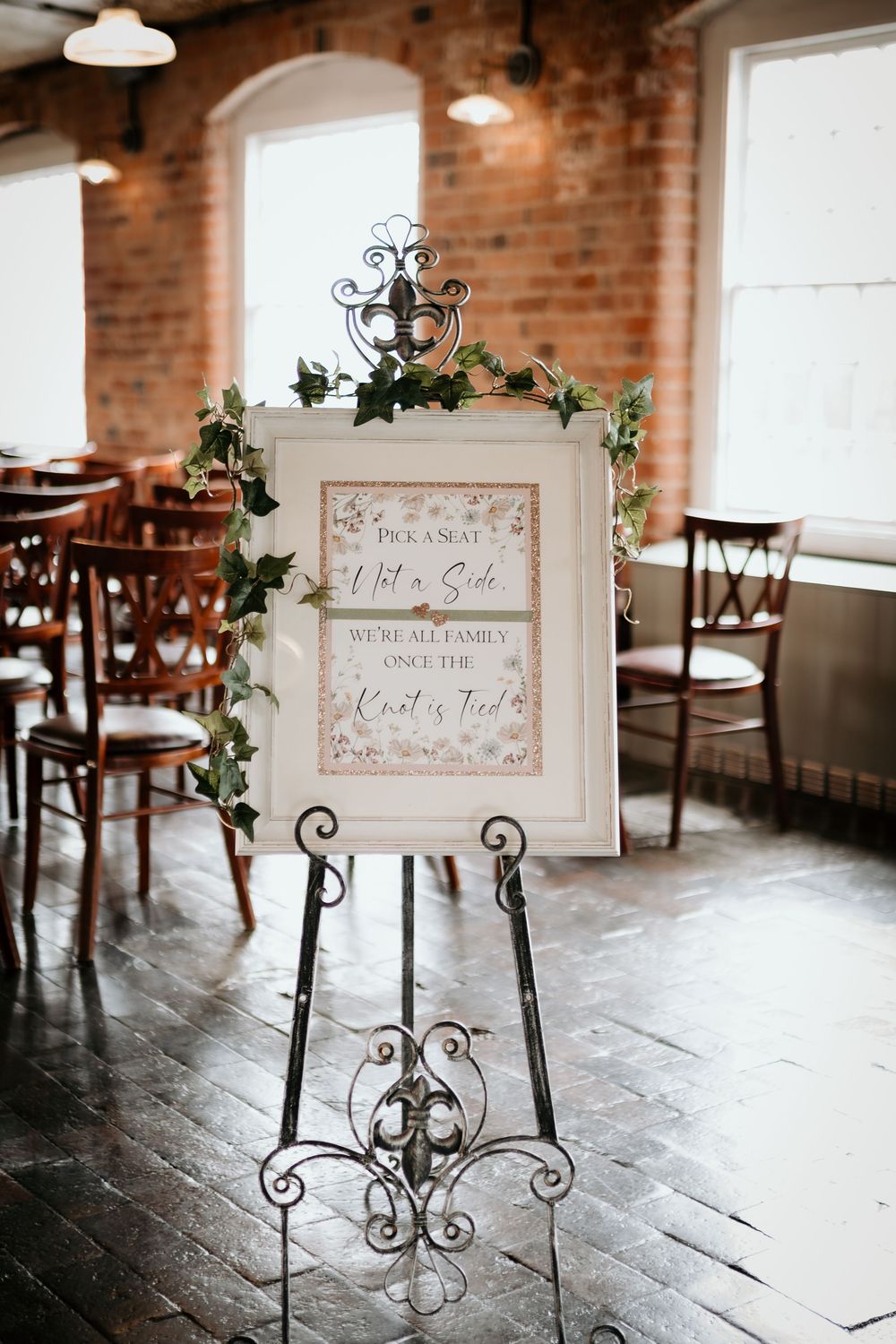 Vintage metal stands with decorative signs on rustic brick floor create an elegant wedding venue display.