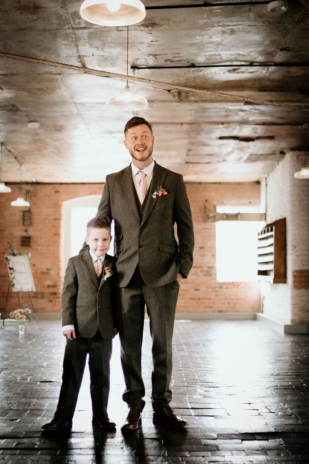 Three artistic black and white photos show a pair in matching suits standing in an industrial brick interior space.